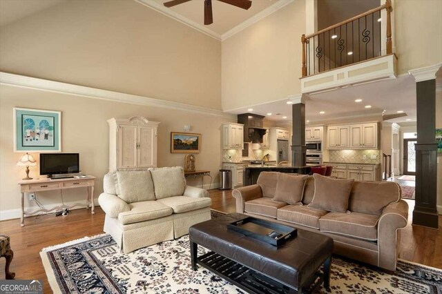 1786 Cambridge Sq, Watkinsville, GA 30677 - living room with a ceiling fan, crown molding, ornate columns, wood finished floors, and high vaulted ceiling
