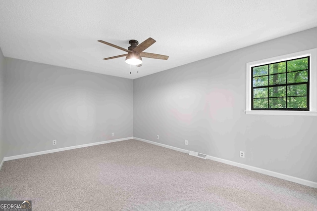 carpeted spare room featuring ceiling fan, baseboards, a textured ceiling, and visible vents