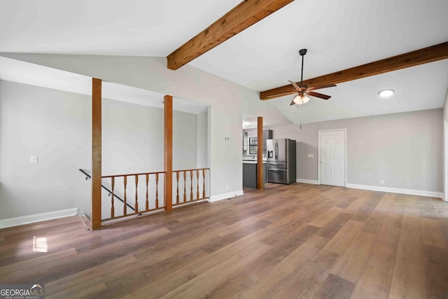 unfurnished living room with wood finished floors, a ceiling fan, and lofted ceiling with beams