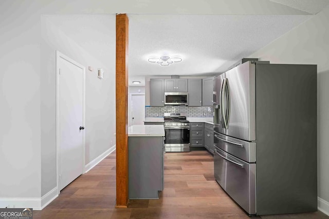 kitchen with light countertops, wood finished floors, gray cabinetry, and appliances with stainless steel finishes