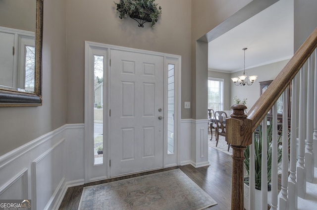 entryway featuring dark wood-type flooring, a wainscoted wall, and a chandelier