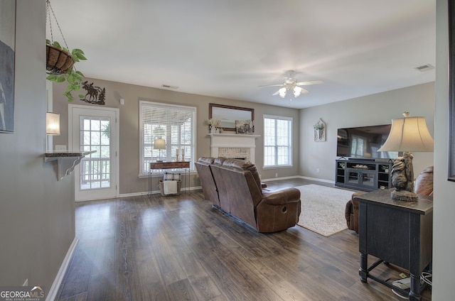 living room with ceiling fan, a fireplace, dark wood finished floors, visible vents, and baseboards