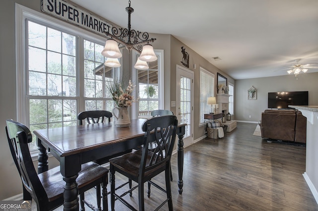 dining area with dark wood-type flooring, visible vents, baseboards, and ceiling fan with notable chandelier
