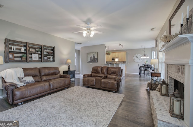 living room with ceiling fan with notable chandelier, dark wood-style flooring, baseboards, and visible vents