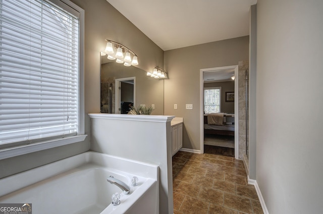 bathroom featuring ensuite bathroom, baseboards, vanity, and a garden tub