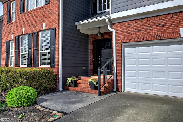 property entrance with a garage, brick siding, and concrete driveway