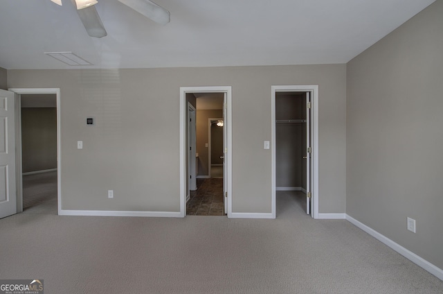 unfurnished bedroom featuring visible vents, baseboards, ceiling fan, a walk in closet, and carpet flooring