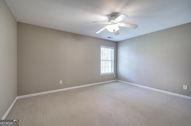 spare room featuring visible vents, baseboards, a ceiling fan, and light colored carpet