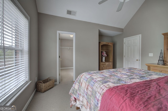 carpeted bedroom featuring visible vents, a closet, a ceiling fan, a walk in closet, and high vaulted ceiling
