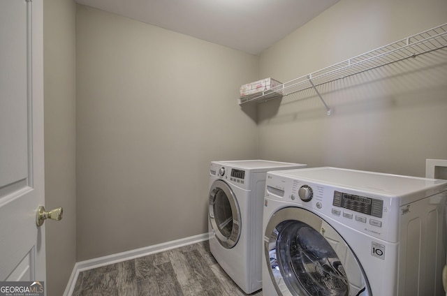 washroom featuring washer and clothes dryer, laundry area, baseboards, and wood finished floors