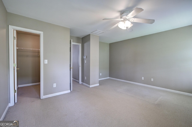 unfurnished bedroom featuring a walk in closet, visible vents, baseboards, and carpet