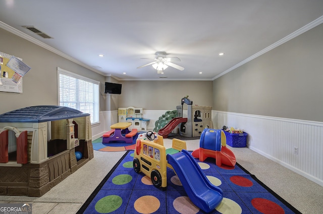 game room featuring ornamental molding, visible vents, a ceiling fan, and wainscoting