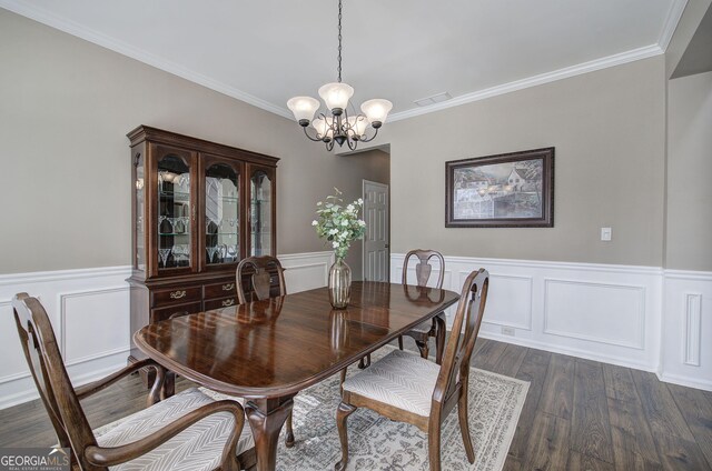 dining room featuring a notable chandelier, ornamental molding, dark wood-style floors, a wainscoted wall, and a decorative wall