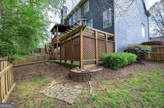 rear view of house featuring a chimney, a fenced backyard, a wooden deck, and stairs