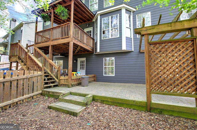 rear view of house with a wooden deck, a patio, and stairs