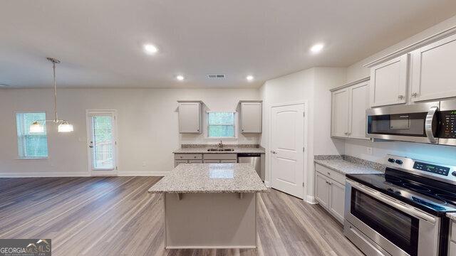 kitchen featuring a sink, appliances with stainless steel finishes, a kitchen island, and light wood-style floors