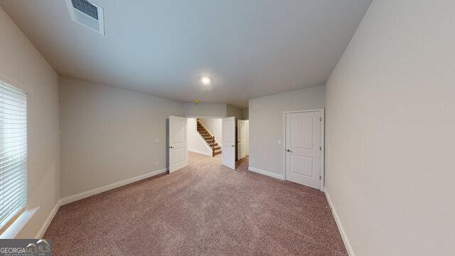 carpeted spare room featuring visible vents, baseboards, and a wealth of natural light