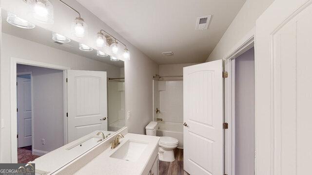 bathroom with toilet, shower / bathtub combination, vanity, and visible vents
