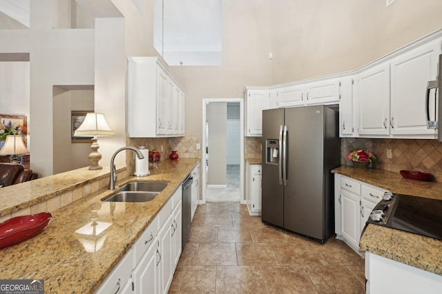 2545 Amberbrook Ln, Grayson, GA 30017 - kitchen featuring a sink, white cabinets, a towering ceiling, and stainless steel appliances