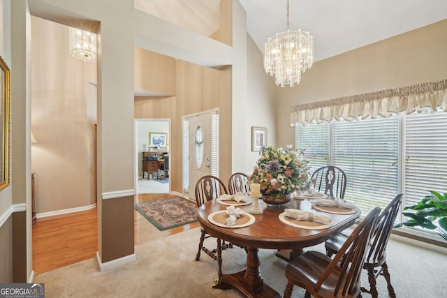 2545 Amberbrook Ln, Grayson, GA 30017 - dining area with light wood-style flooring, light colored carpet, a towering ceiling, a chandelier, and baseboards