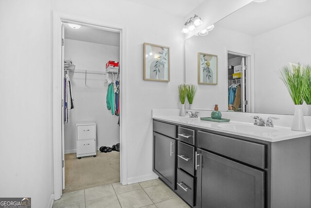 full bathroom featuring double vanity, a spacious closet, tile patterned flooring, and a sink