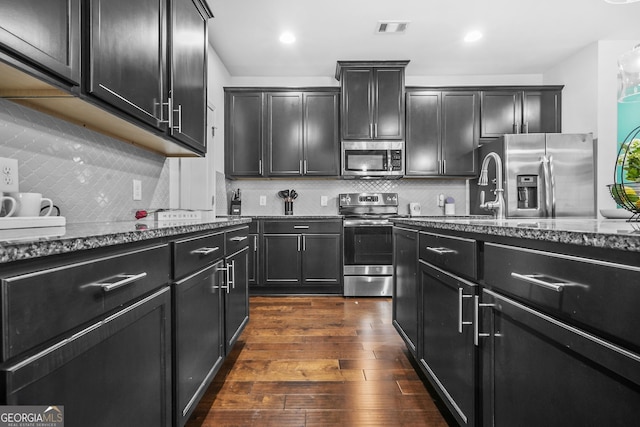 kitchen with visible vents, dark cabinetry, dark stone counters, and appliances with stainless steel finishes