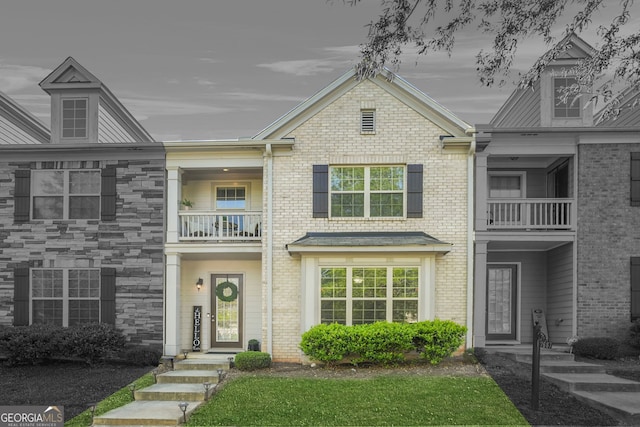 view of front of house with brick siding and a balcony