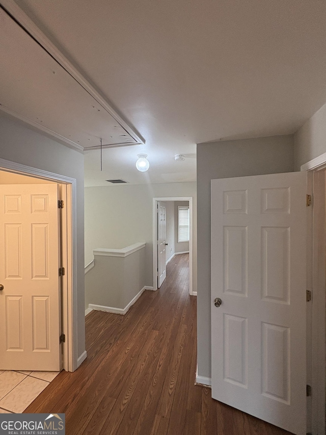 hall featuring wood finished floors, attic access, baseboards, and visible vents