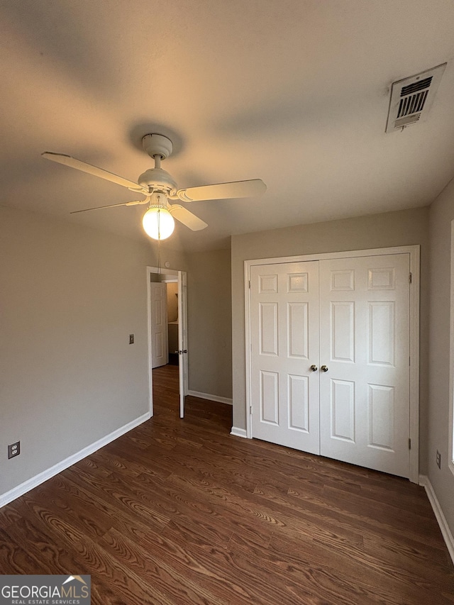 unfurnished bedroom featuring visible vents, baseboards, a closet, ceiling fan, and dark wood-type flooring