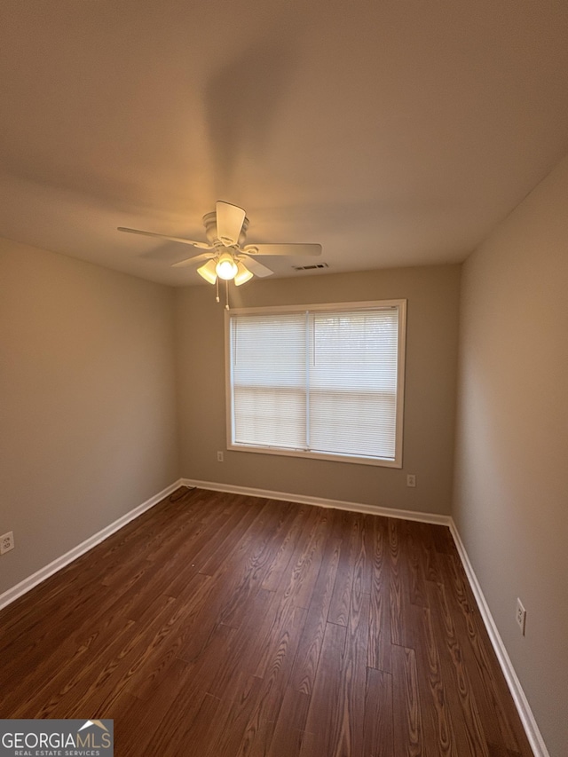 spare room with ceiling fan, baseboards, dark wood finished floors, and visible vents