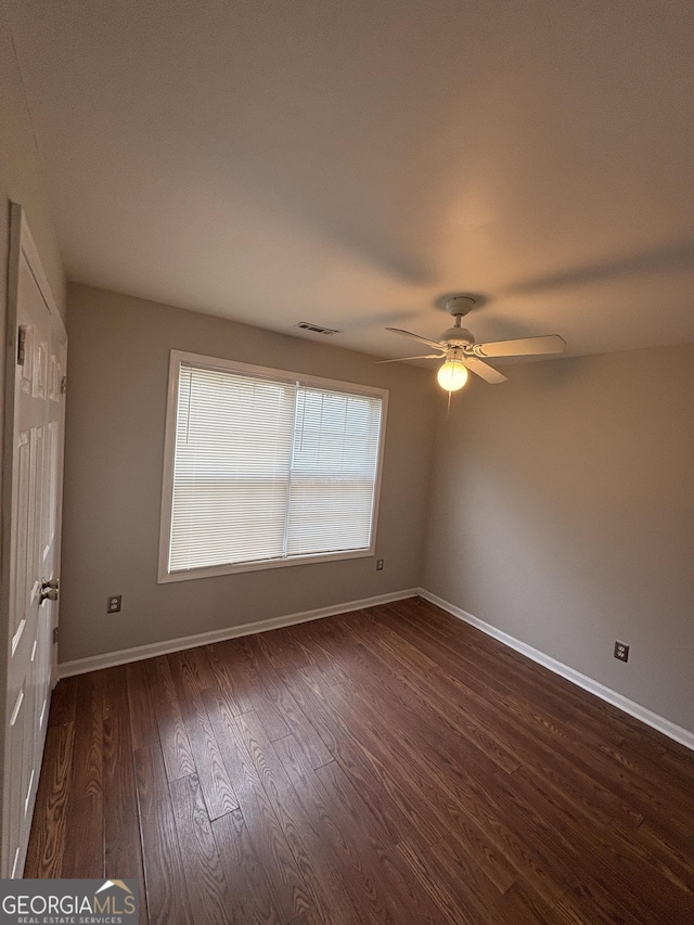 spare room featuring a ceiling fan, baseboards, dark wood finished floors, and visible vents