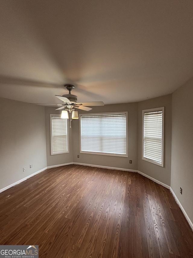 spare room with ceiling fan, dark wood-style flooring, and baseboards