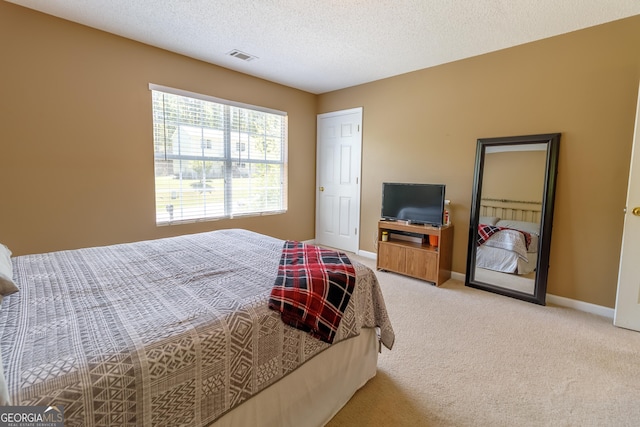 carpeted bedroom featuring visible vents, baseboards, and a textured ceiling