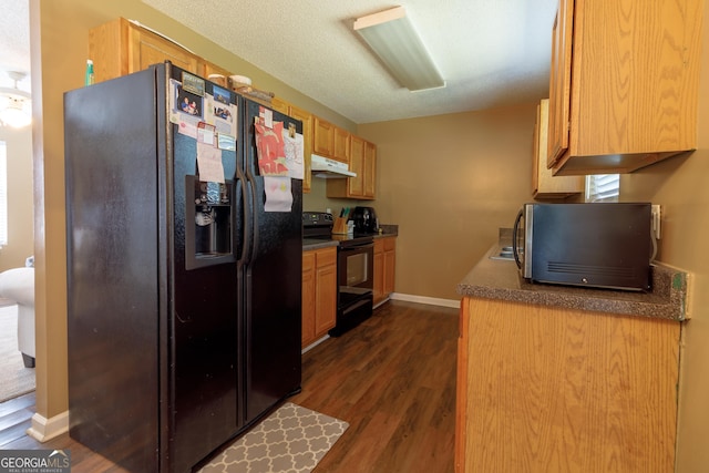 kitchen with dark countertops, black appliances, dark wood-style flooring, and under cabinet range hood