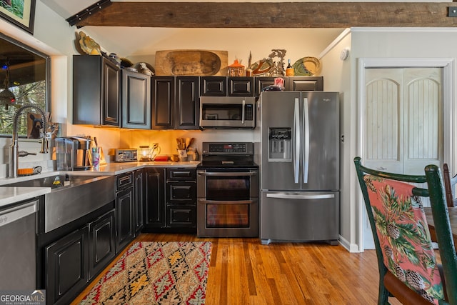 kitchen with stainless steel appliances, light wood-style floors, light countertops, and a sink