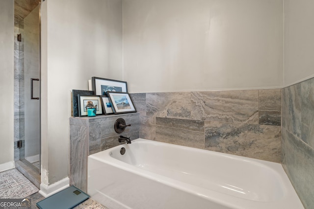 bathroom featuring a stall shower, a garden tub, and baseboards
