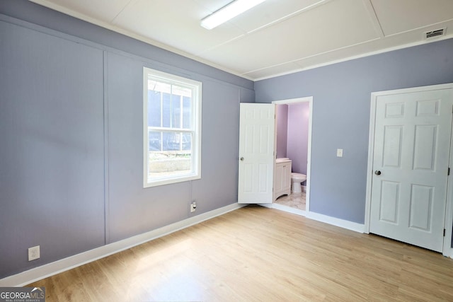 unfurnished bedroom featuring ensuite bath, visible vents, light wood-type flooring, and baseboards
