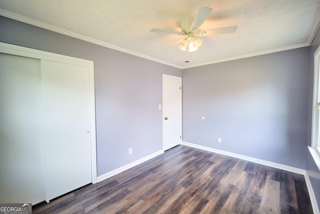 unfurnished bedroom with ceiling fan, dark wood-type flooring, a closet, ornamental molding, and baseboards