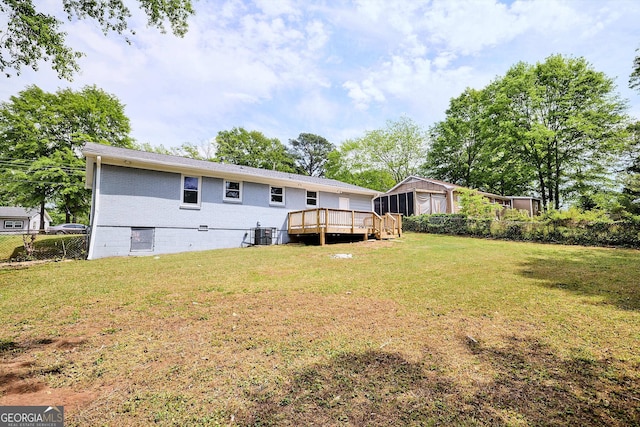 back of house with cooling unit, brick siding, a wooden deck, a yard, and fence