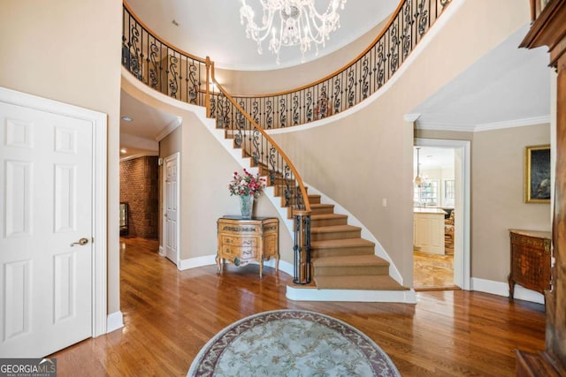 foyer entrance with an inviting chandelier, ornamental molding, wood finished floors, stairs, and baseboards