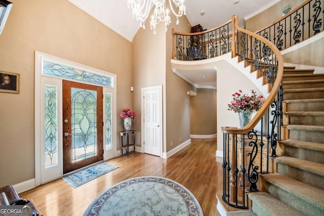 entryway featuring ornamental molding, baseboards, an inviting chandelier, and wood finished floors