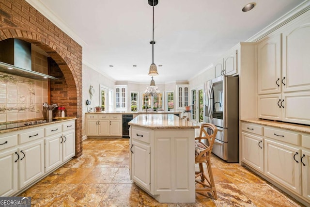kitchen featuring a center island, wall chimney range hood, stainless steel fridge, and a wealth of natural light