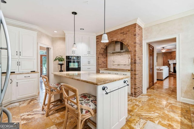 kitchen featuring light stone countertops, white cabinetry, oven, and stainless steel fridge