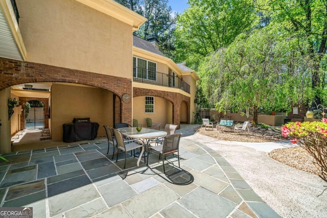 view of patio / terrace featuring a grill, outdoor dining space, fence, and a balcony