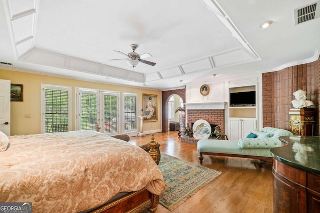 bedroom featuring visible vents, a brick fireplace, ornamental molding, wood finished floors, and access to exterior