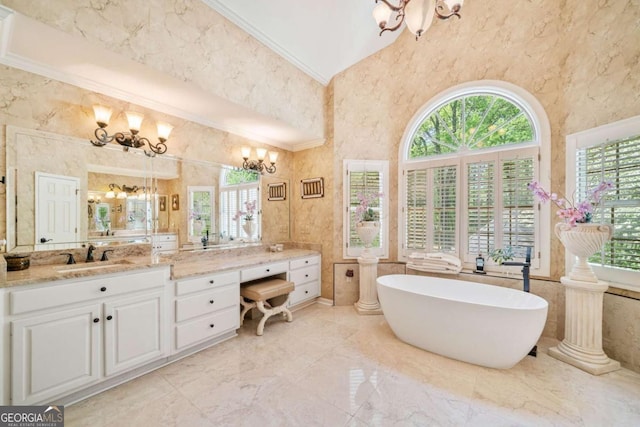 full bath with a freestanding tub, an inviting chandelier, marble finish floor, and vanity