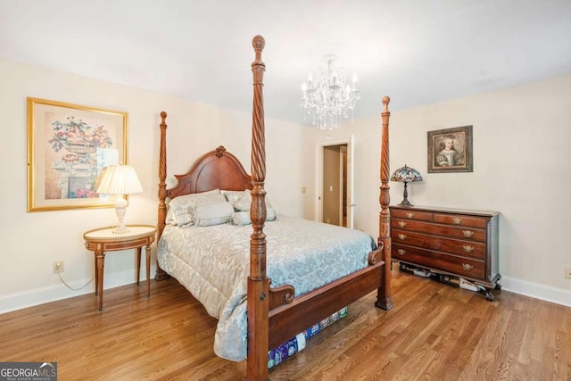 bedroom featuring a chandelier, wood finished floors, and baseboards