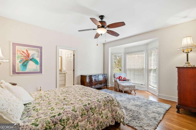 bedroom with ensuite bath, baseboards, a ceiling fan, and wood finished floors