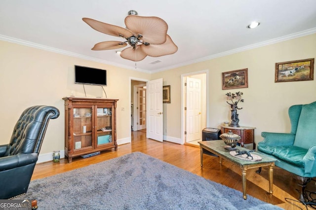 living room featuring crown molding, ceiling fan, wood finished floors, and baseboards