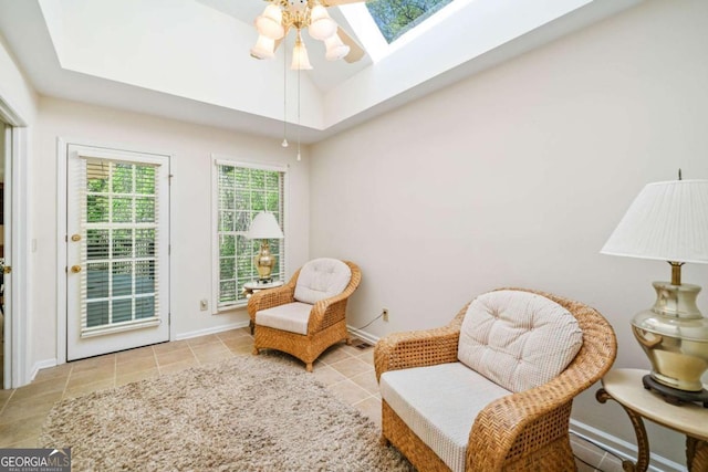 sitting room featuring tile patterned flooring, ceiling fan, baseboards, and a skylight